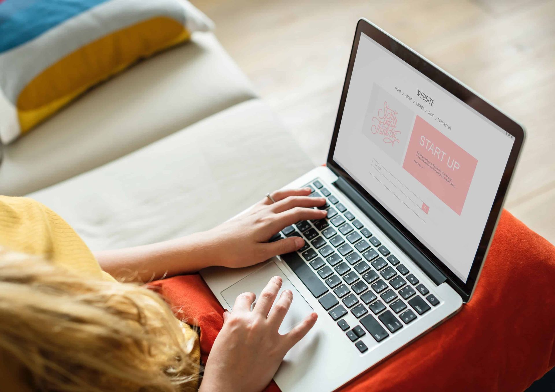 Someone working on a laptop from a couch, collaborating remotely