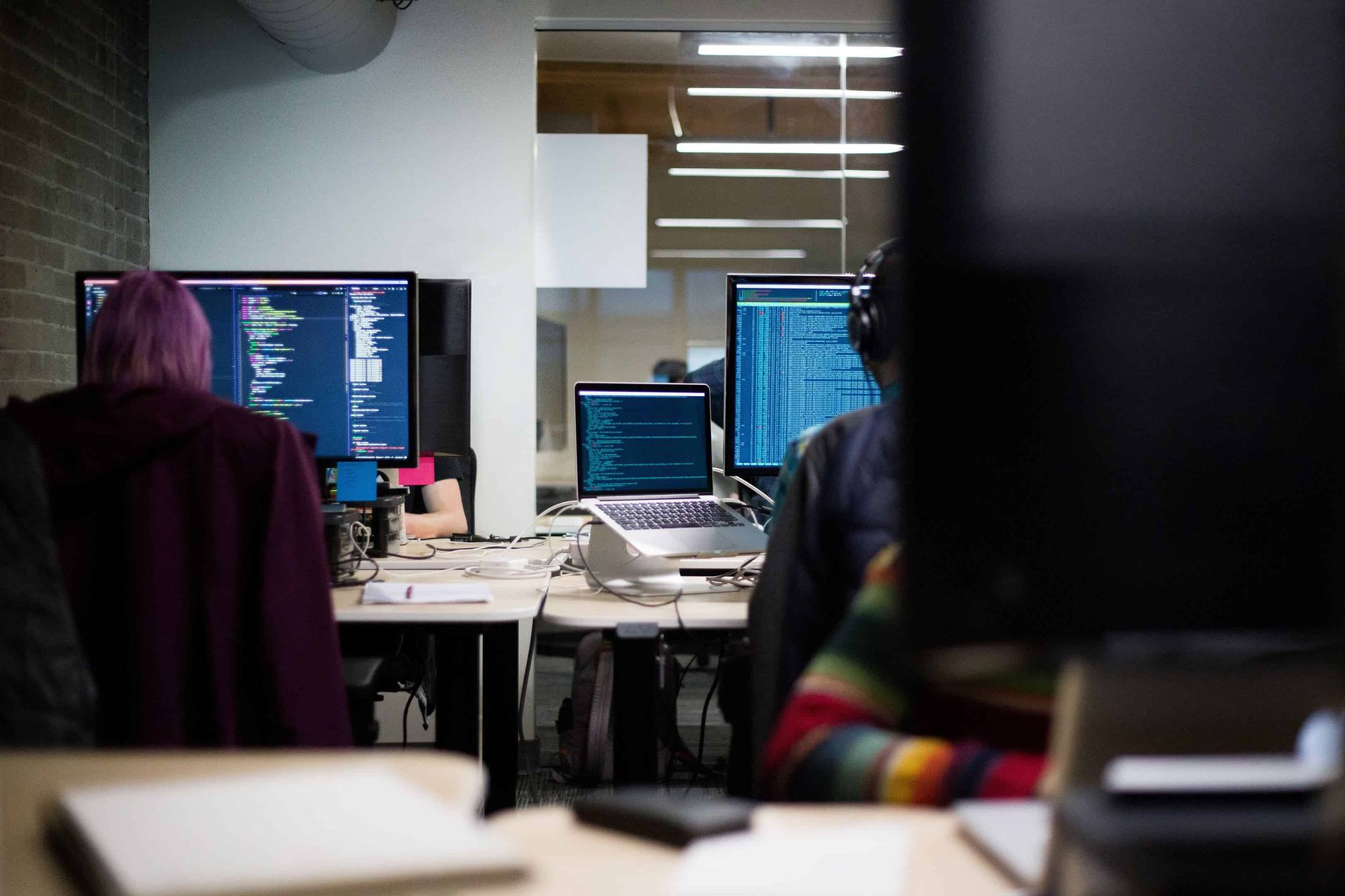 Developers writing code at a bank of monitors in an open-plan office